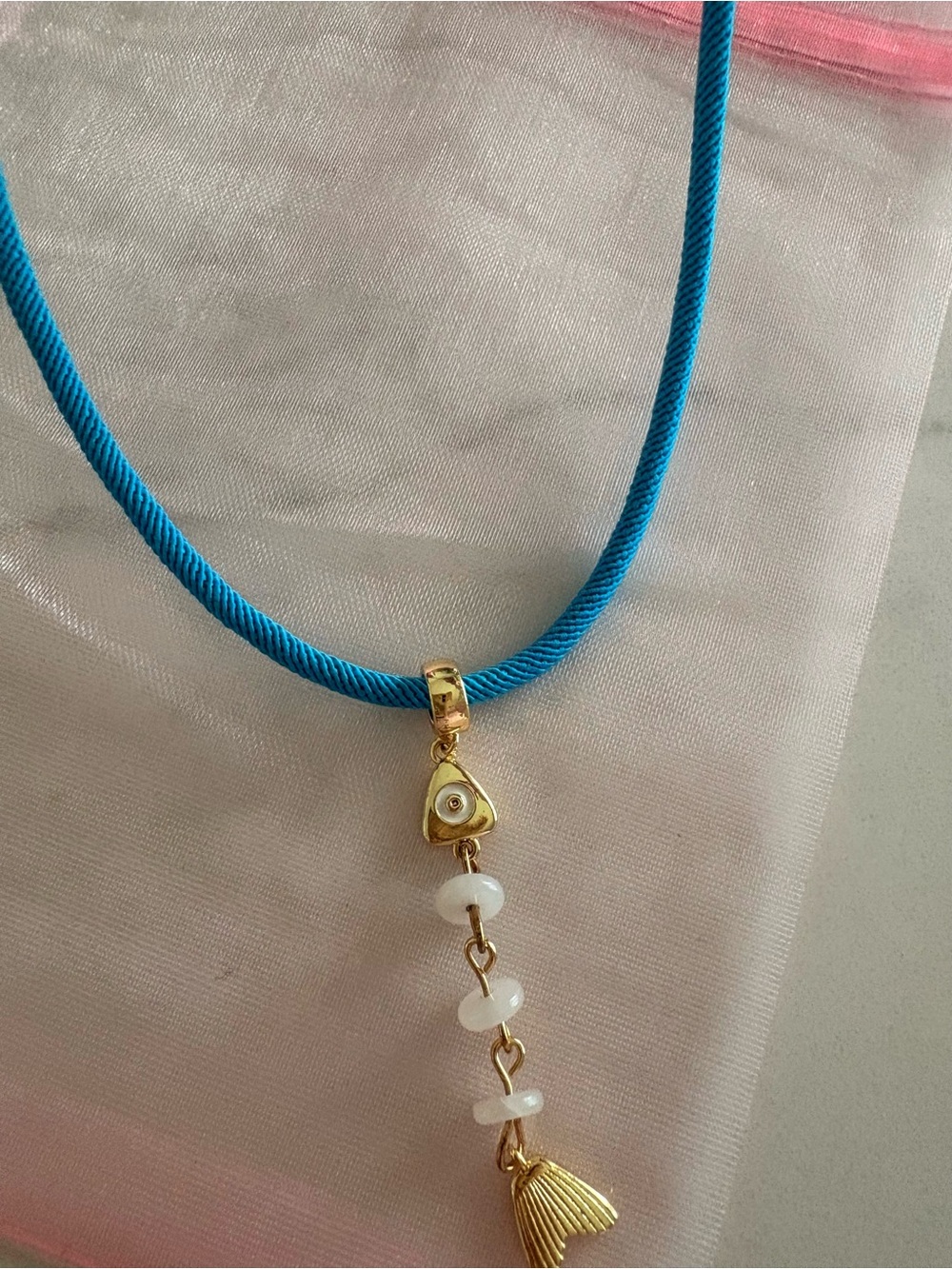 Blue cord necklace with gold tone fish charm.